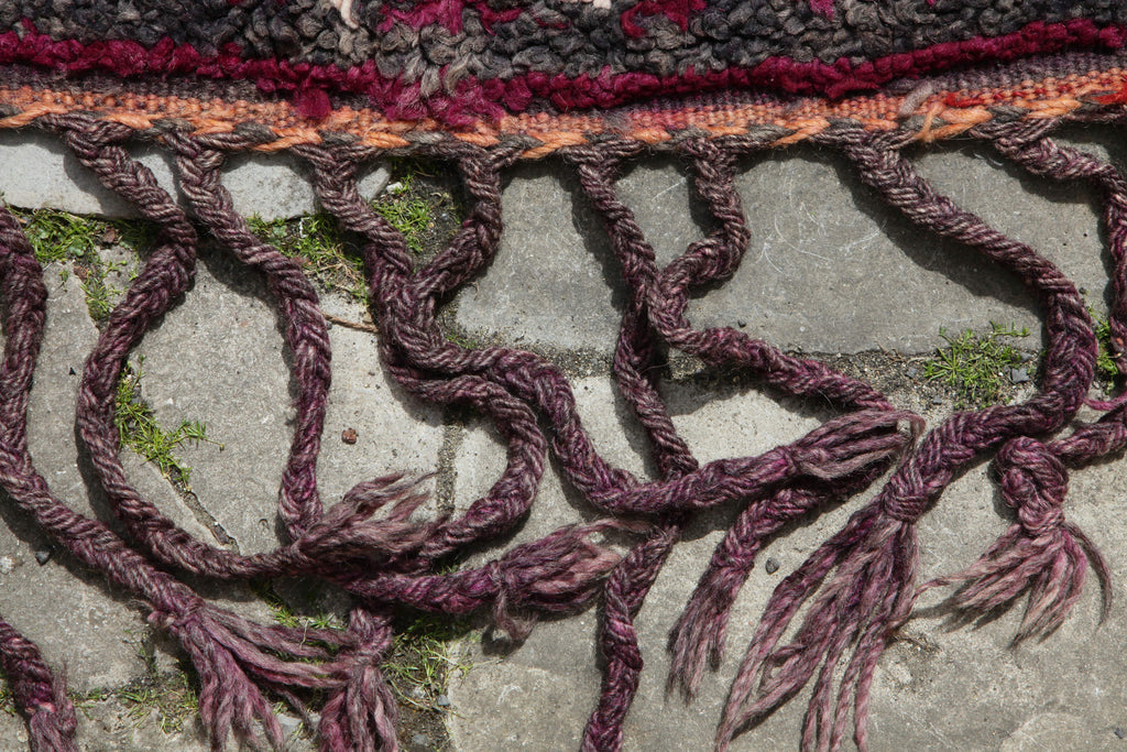 Close-up of the end of the Khenifra Beni M'Guild rug showing long tassels formed from the warp strands.