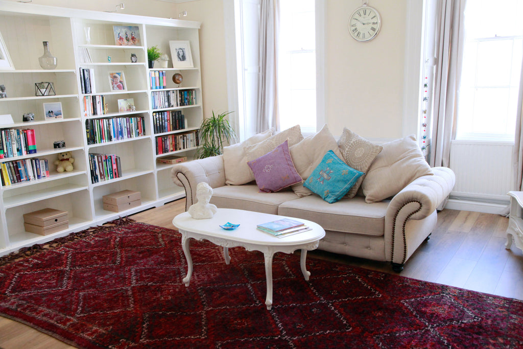 Beni M'Guild rug beautifully matching a classical sitting room setting with Queen Anne style coffee table and sofa and wall-to-wall white bookshelf.