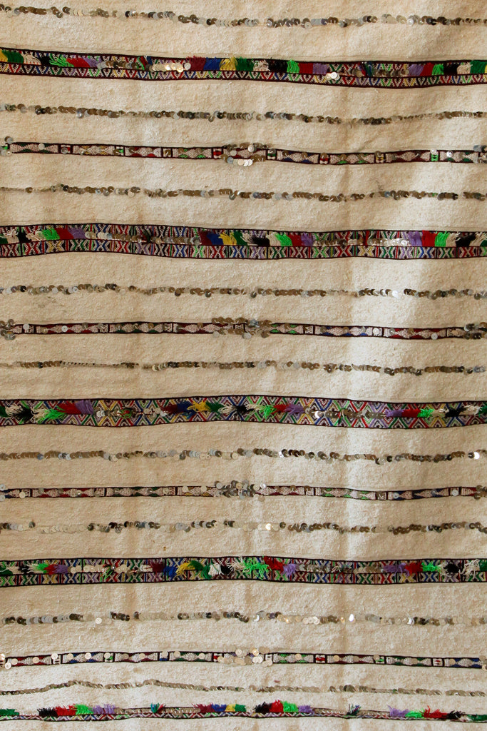 Detailed Moroccan ceremonial wedding blanket with metal sequins and bands of colourful Berber symbols.