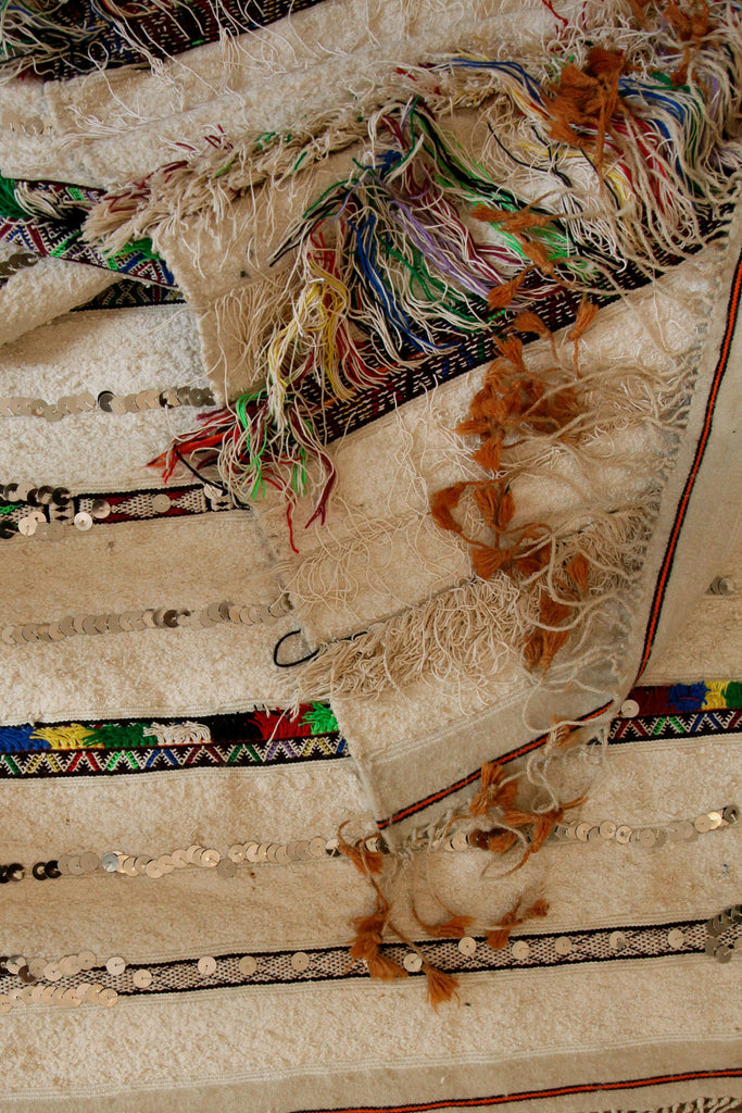 Extreme close-up of the Moroccan ceremonial wedding blanket showing tassels and detailed embroidery.